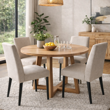 Round messmate timber dining table styled in a modern home with upholstered dining chairs