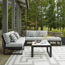 Modern outdoor modular sofa set with geometric cushions and coffee table on patio